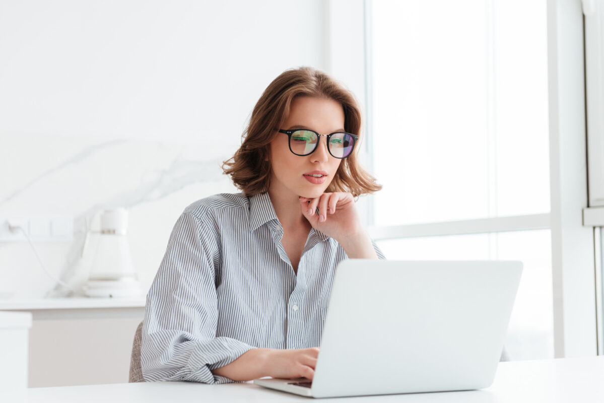 charming businesswoman glasses striped shirt working with laptop computer while siting home