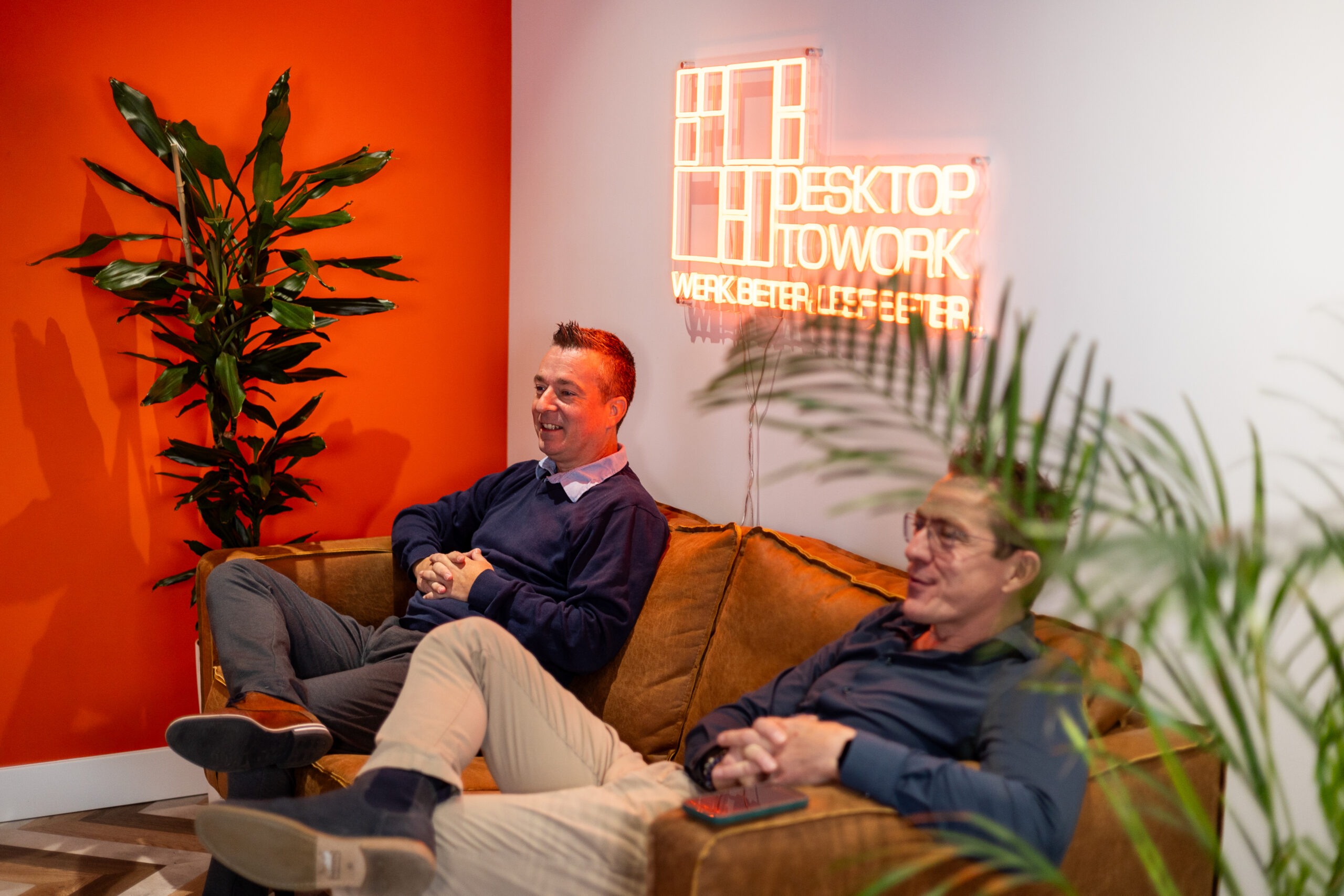 Collega's van DesktopToWork in gesprek op de bank in het kantoor in Den Haag